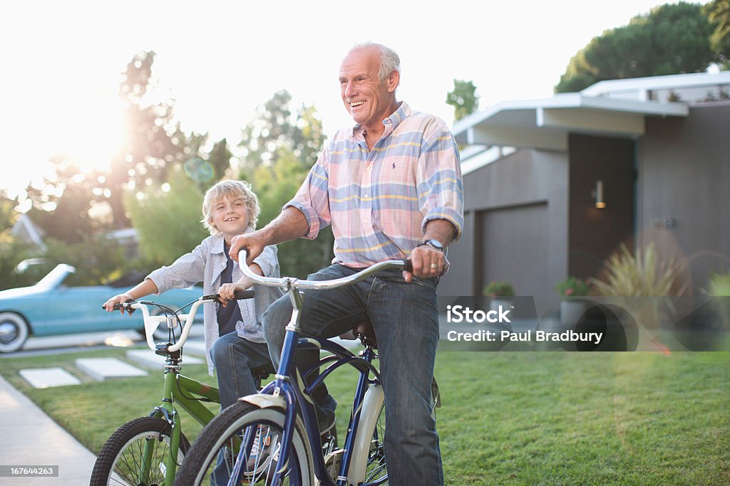 Hombre mayor envenenado y nieto montando una bicicleta al aire libre - Foto de stock de 10-11 años libre de derechos