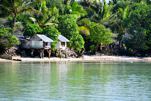 Banraeaba, Ambo motu, South Tarawa, Kiribati: village houses, built on stilts over the beach with tropical forest in the background.