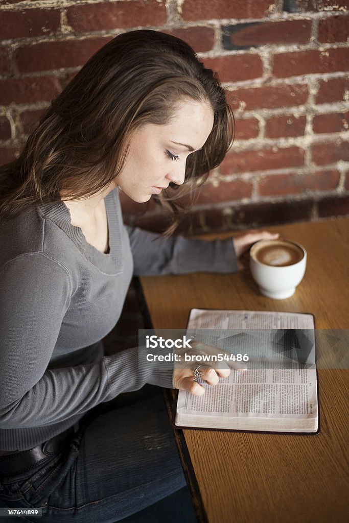 Young Woman with White Coffee Cup Reads Her Bible Portrait of a young woman with a white coffee cup reading the book of Mark in the Bible 20-24 Years Stock Photo