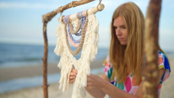 istock A woman weaves macrame on the beach at sunset. 1676474398