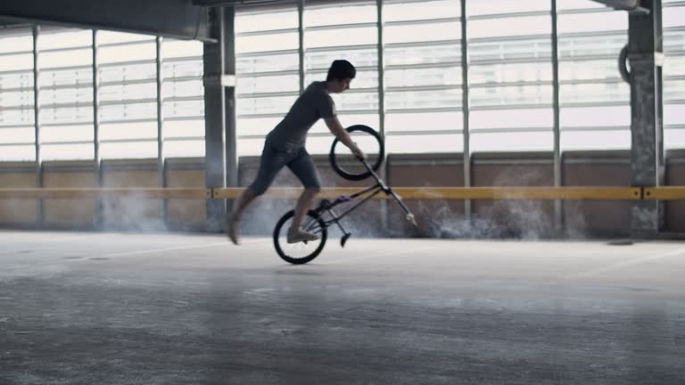 Young male rider performing peg manual flatland trick on BMX