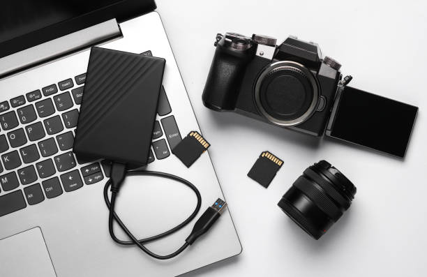 laptop, external hard drive, modern digital camera with flip screen, two sd memory cards and lens on gray background. photographer's equipment. top view. flat lay - memory card imagens e fotografias de stock