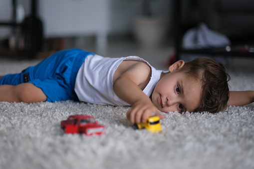 little boy playing with toy cars on the carpet