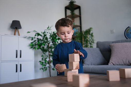 little boy making blocks with wooden cubes