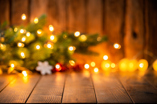 Empty wooden table with blurred Christmas lights and pine branch at background. High resolution 42Mp studio digital capture taken with SONY A7rII and Canon EF 70-200mm f/2.8L IS II USM Telephoto Zoom Lens