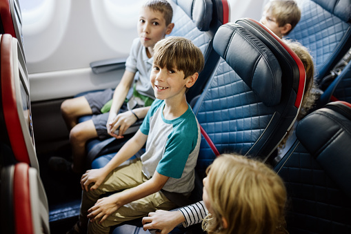 A Caucasian family with multiple children on vacation depart from the airport on a plane.