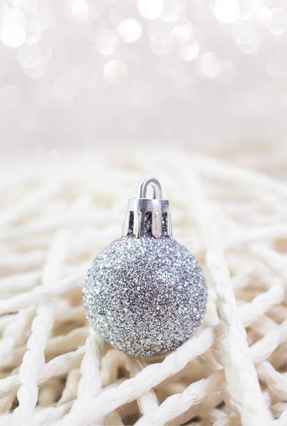 Christmas New Year's silver toy on background handmade from threads. Defocus bokeh, soft focus. Vertical. Copy space