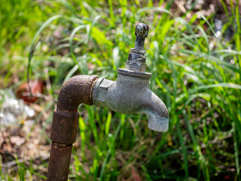 An old tap, covered in lime-scale, in a public park.