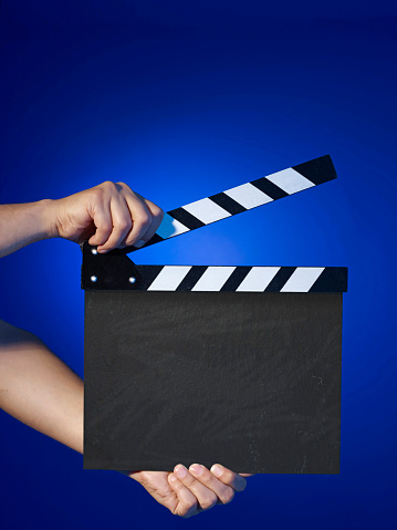 Man holding blank film slate on blue background
