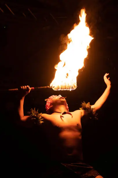 Photo of Hawaiian male dancer with torch in hands.