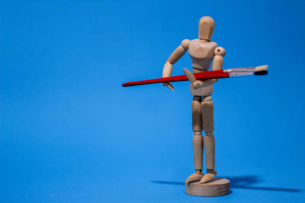 istock Wooden mannequin holding painting brushes 1676609634