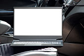 A laptop with a white screen stands on the seat in the car, work and business trip, space for text on the laptop, laptop