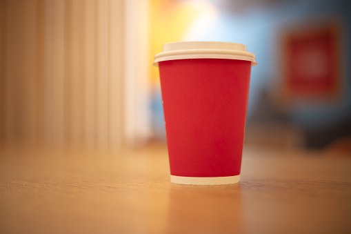 Red take-away coffee cup on the cafe table.