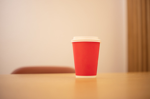 Red take-away coffee cup on the cafe table.