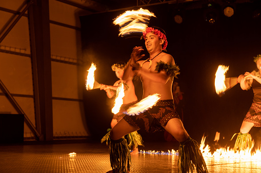 Hawaiian male dancer twirls torch with hands.