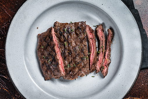 Homemade Cooked Skirt steak on a grill.  Dark background. Top view.