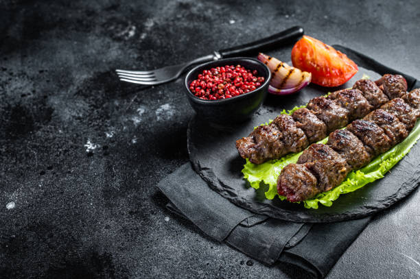 kebab d’urfa grillé avec tomate, salade et oignon. fond noir. vue de dessus. espace de copie - lamb kebab kofta ground photos et images de collection