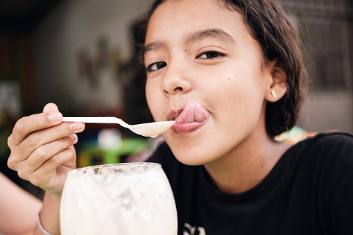 adolescent woman savoring glass of ice cream