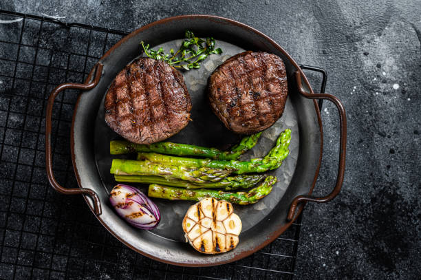 istock Grilled Fillet Mignon Steak with roasted asparagus. Black background. Top view 1676643498