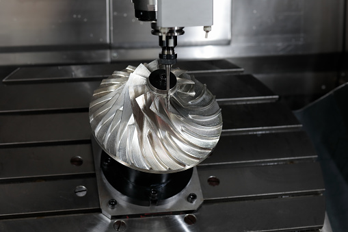 A manufacturing worker holding a formed metal part made by a brake press. Formed metal parts are made using brake presses and laser cutting CNC machines.