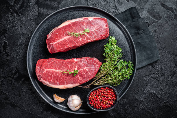 istock Dry aged Raw top blade flat Iron beef meat steaks. Black background. Top View 1676660917