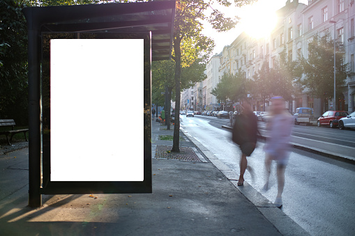 Blank electronic advertising space at bus stop with commuters