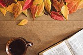 Bible, cup of coffee and autumn leaves on wood