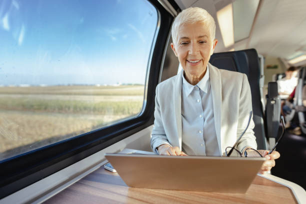 istock Senior woman working on laptop in the train 1676708541