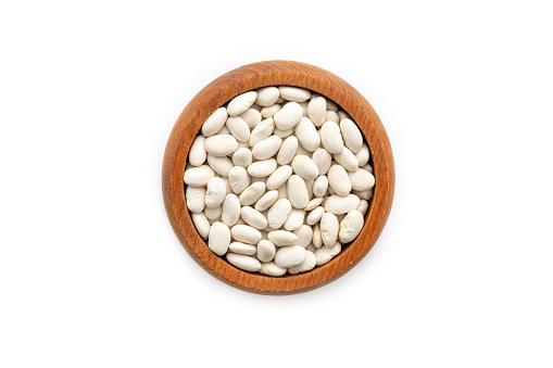 Wooden bowl full of White beans isolated on white background.