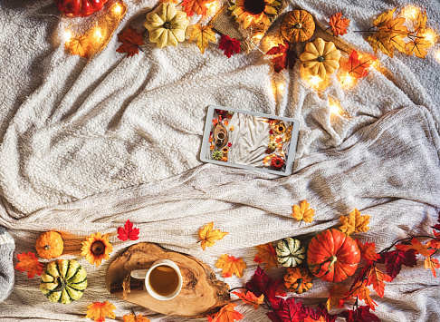 Digital tablet on decorated autumn background with leaves and pumpkins. Free space for text. Cozy home concept