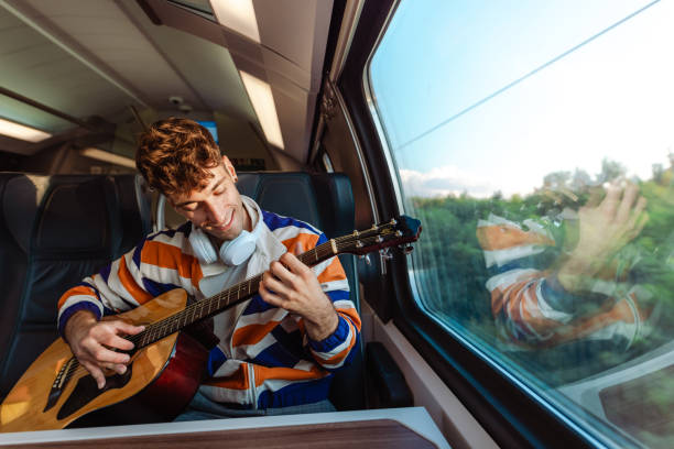 istock Young man playing a guitar during a train ride 1676731751