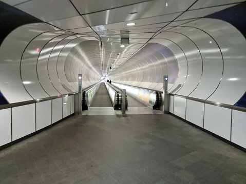 Dark interior of subway station with modern train with closing doors; perspective view of empty underground platform with contemporary black metro train with yellow stripes; Porto, Portugal