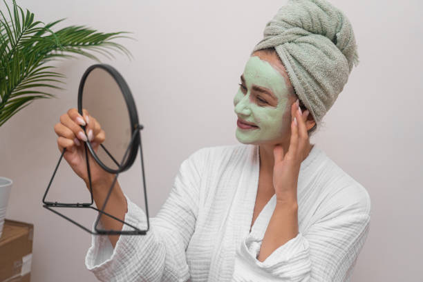 istock joyful lady, in a gown, smiles while gazing mirror, using a homemade mask for a refreshing skincare 1676831019