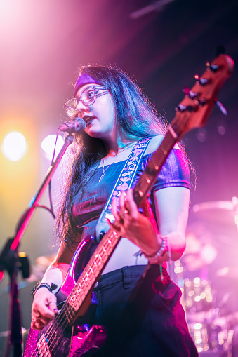 A beautiful 21 year old female bass player and singer performing live on stage.