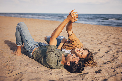 Young man and woman in sunglasses lying on seashore. concept