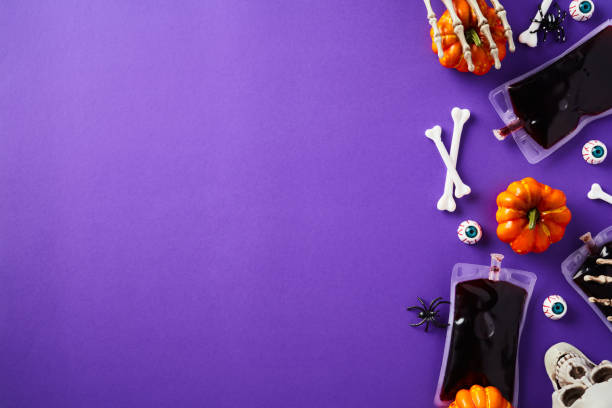 istock Happy Halloween holiday flat lay composition with blood packets, bones, eyes, skull, pumpkin on purple background. Top view with copy space. 1676840833