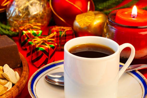 Coffee break at home with black coffee , chocolate bars and cashew over red color table , also Christmas light and red candle with flame.