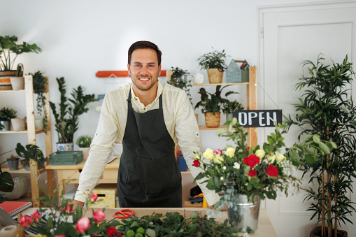 Portrait of young handsome man working at flower shop