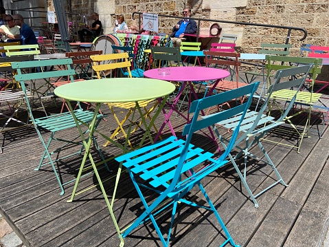 Paris, France - June 10, 2022 : A group of colorful metal tables and folding chairs at an outdoor cafe along the Seine River on a sunny day in Paris