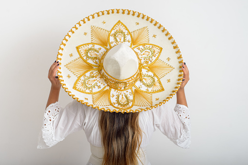 Portrait of woman from behind wearing mariachi hat. Woman with hat, white background.