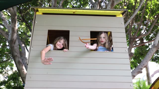 Children playhouse and little girls waving