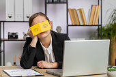 Inefficient tired lazy business woman working sleeping on laptop computer with eyes stickers on face