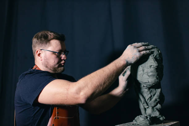 istock Man sculptor creates sculpt bust clay human woman sculpture. Statue craft creation workshop 1677062893