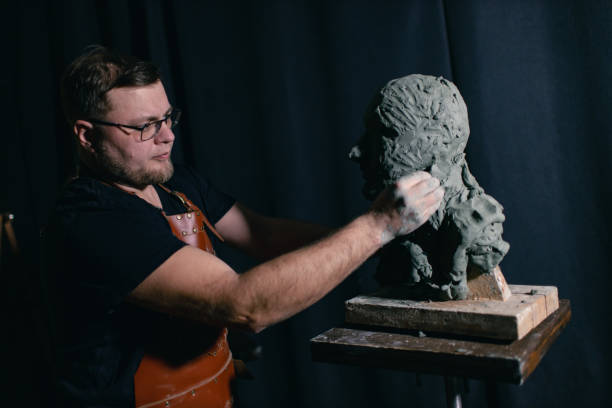 istock Man sculptor creates sculpt bust clay human woman sculpture. Statue craft creation workshop 1677062895
