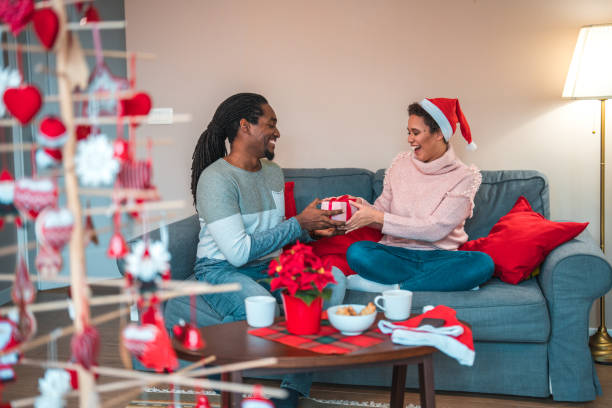 beau couple souriant échangeant des cadeaux de noël à la maison - 11705 photos et images de collection