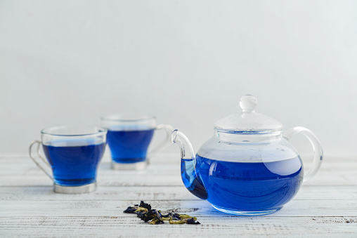 Two glass cup of blue Anchan tea with teapot  on white wooden backgroud