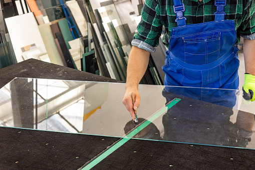 A glazier cuts glass in a glass factory
