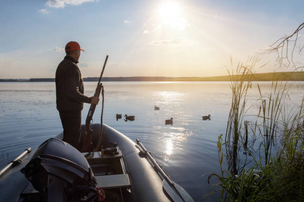 istock Duck Hunter in boat on a sunset background. Hunter in boat hunting ducks. 1677196389