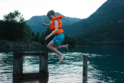 boy jumping into a Norwegian Fjord from a dock in Stryn, Vestland, Norway