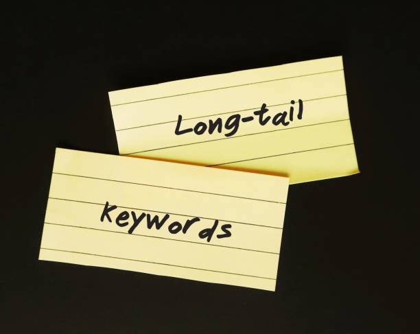 yellow note paper on black background with handwritten text long-tail keywords, unpopular phrases users search less, keywords or keyphrases more specific and get less search traffic - tail long marketing internet imagens e fotografias de stock